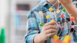 A child building a structure using toothpicks and jube lollies