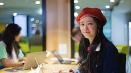 An international student wearing red beret and smiling at the camera