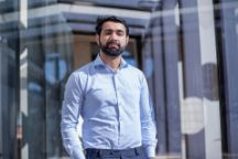A male international student wearing a blue shirt looking into the camera