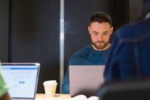 An international working on an assignment using a laptop in the library