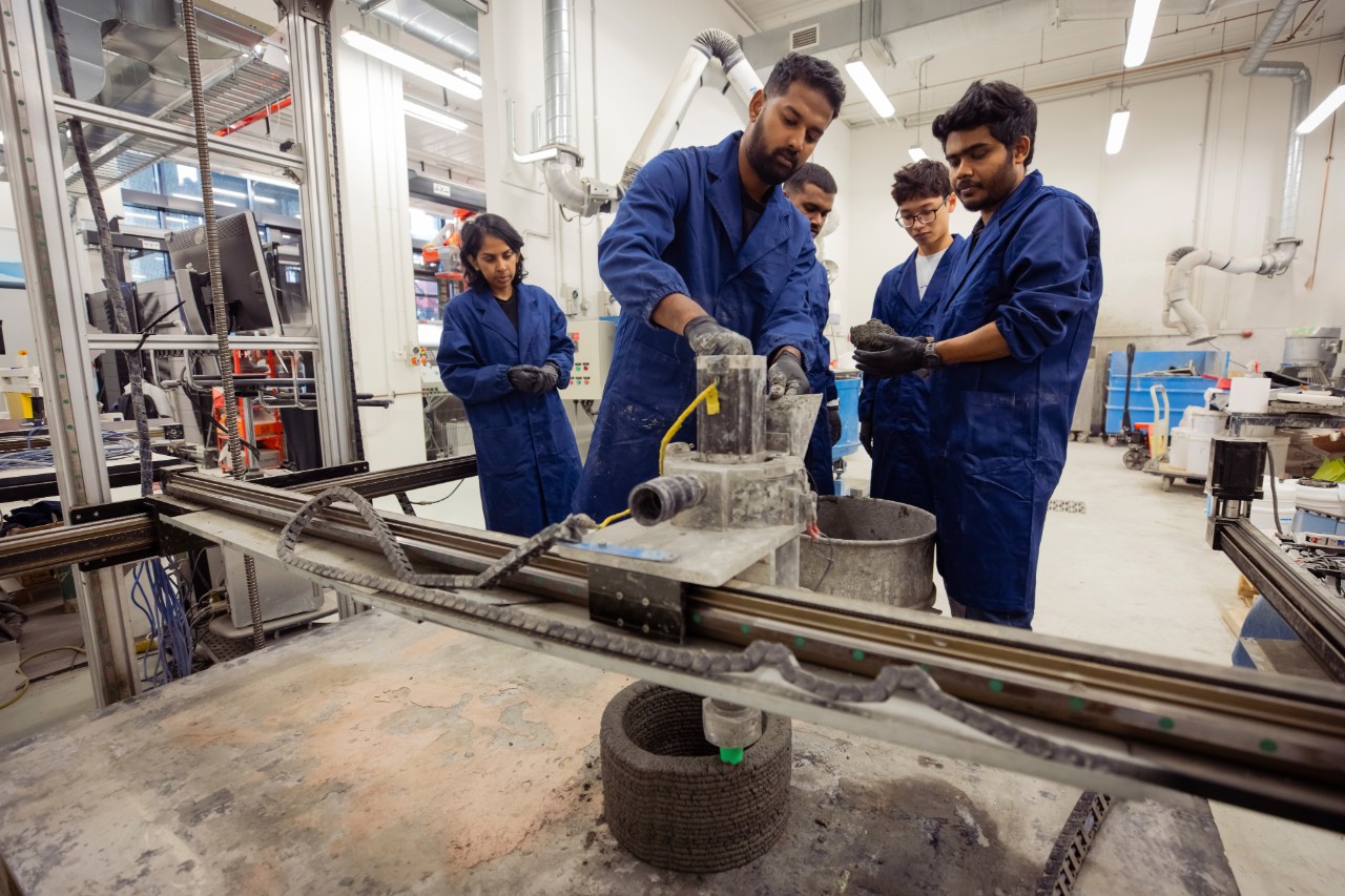 Students shoveling concrete into the medium-scale 3D concrete printer in the Digital Construction Lab.