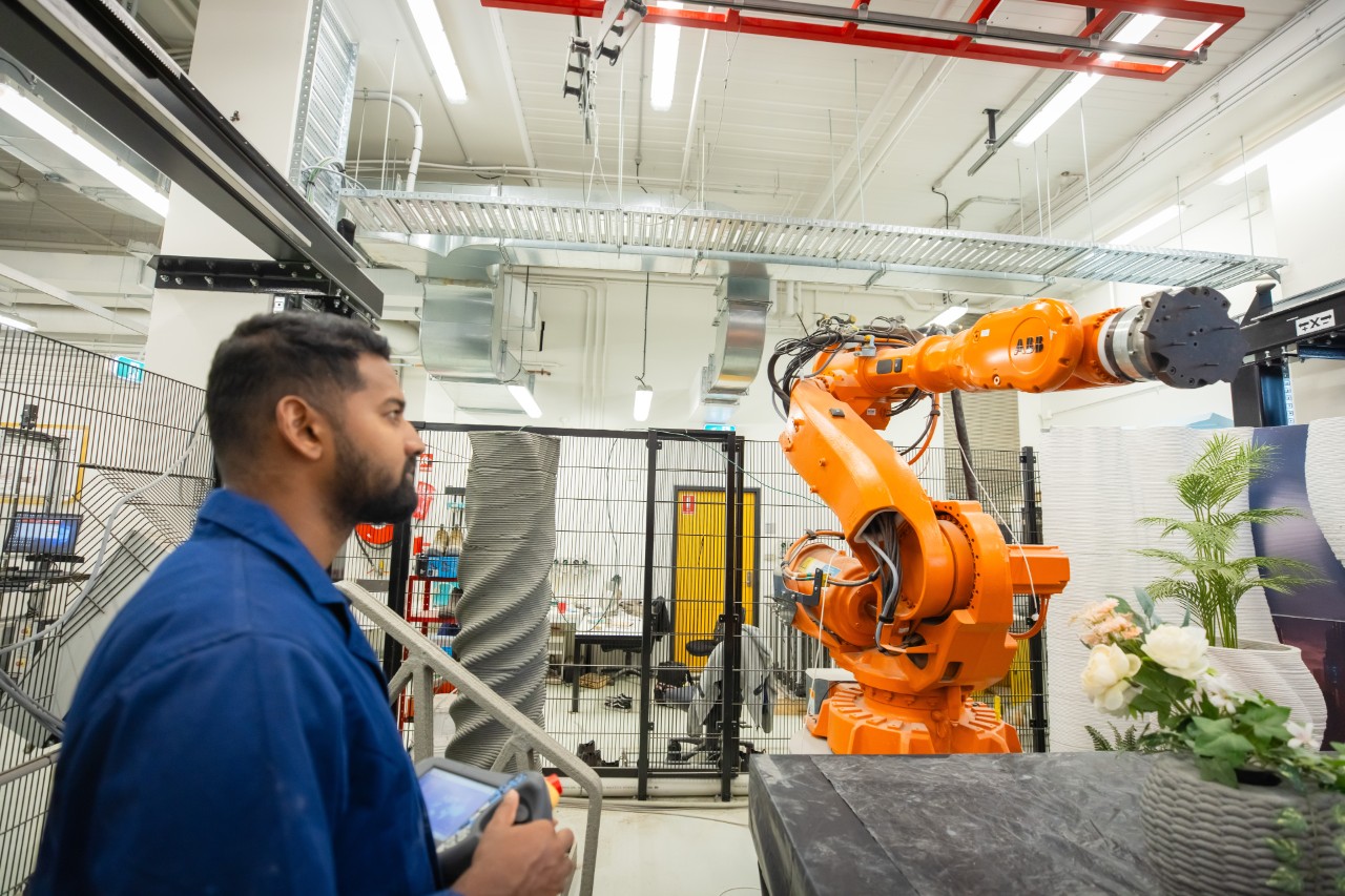 A student controlling the robotic arm of a concrete printing robot in the Digital Construction Lab.
