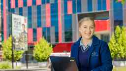 School aged student in uniform sitting on the grass at Hawthorn campus