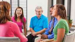 Happy diverse people discussing things in therapy support meeting