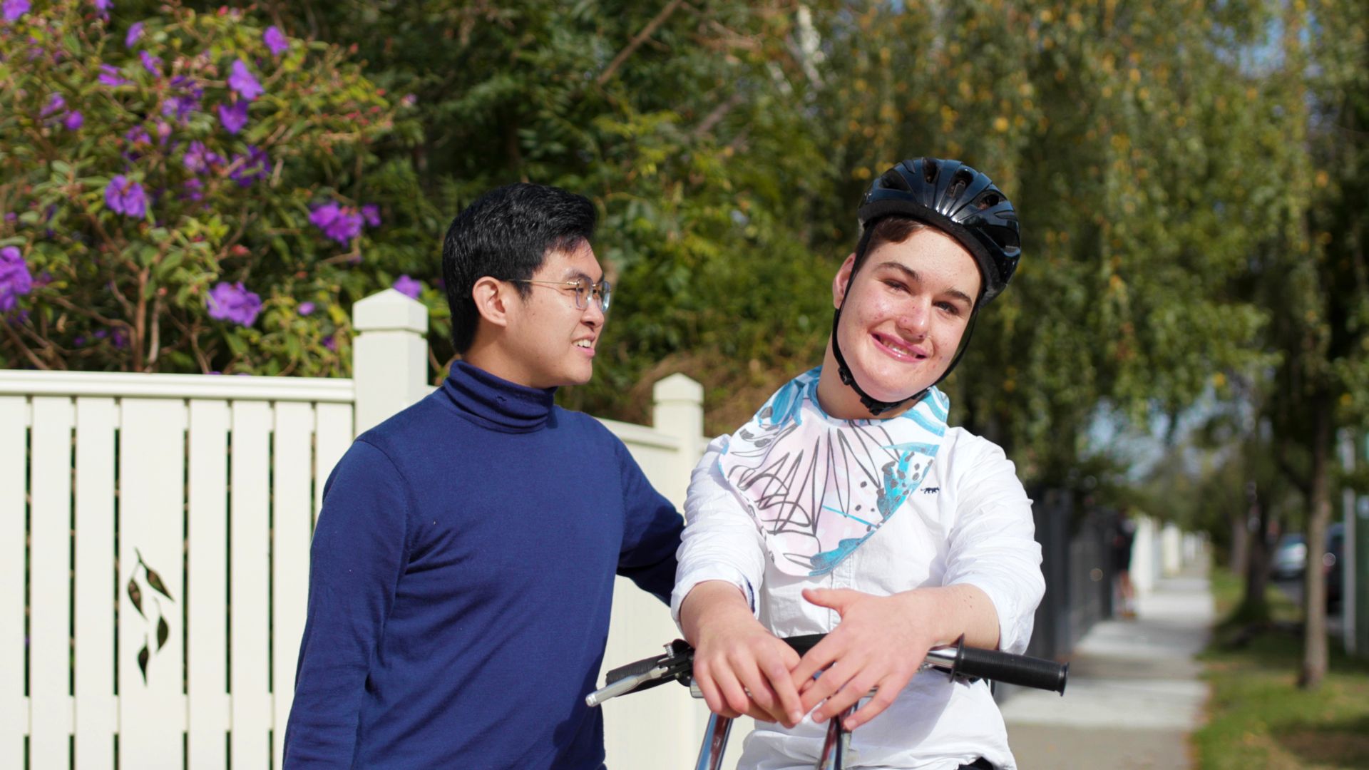 A placement student accompanying a disabled child on a walk outside a house