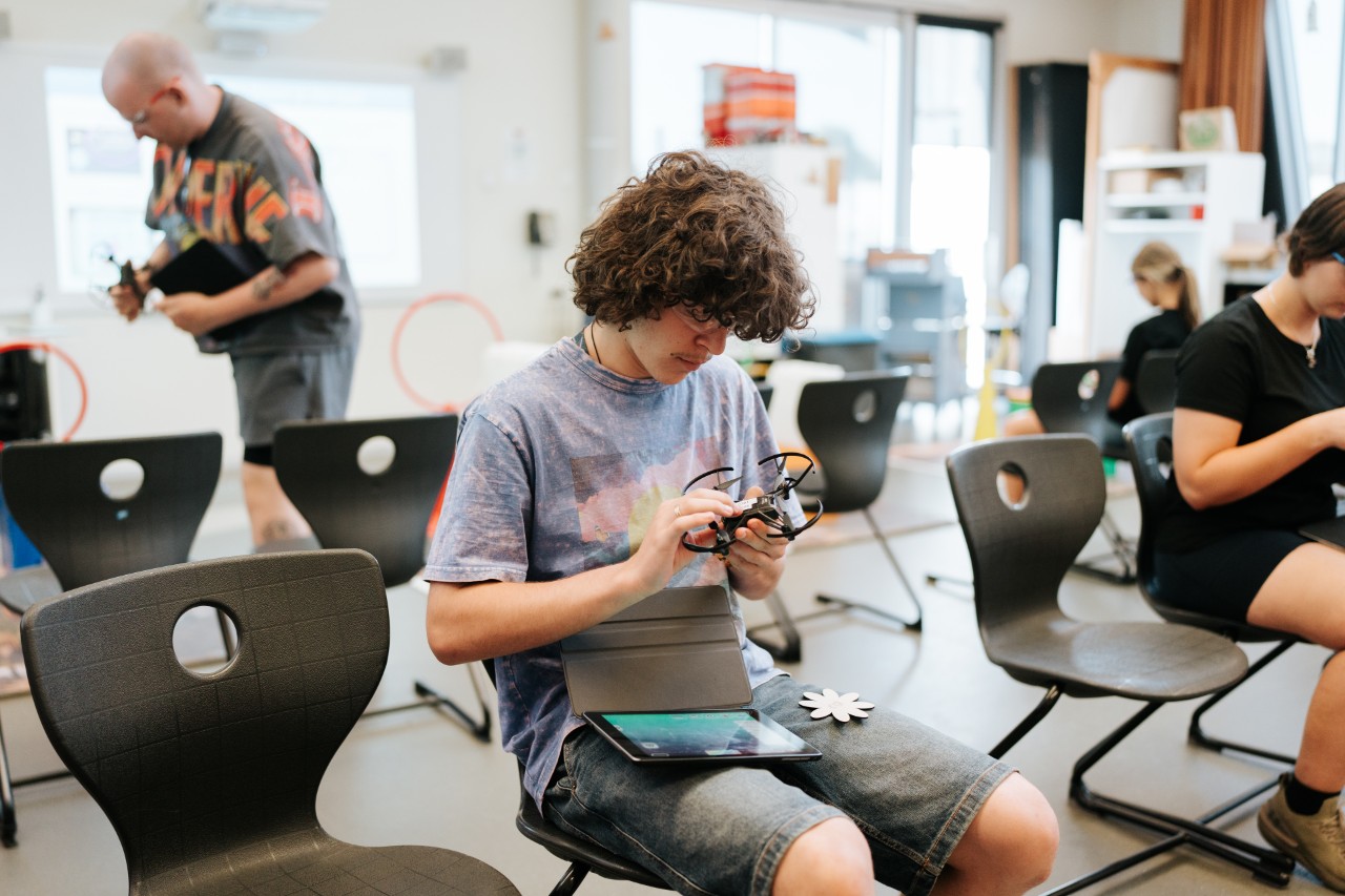 Male young adult tinkering with tech, with an iPad sitting on his lap.