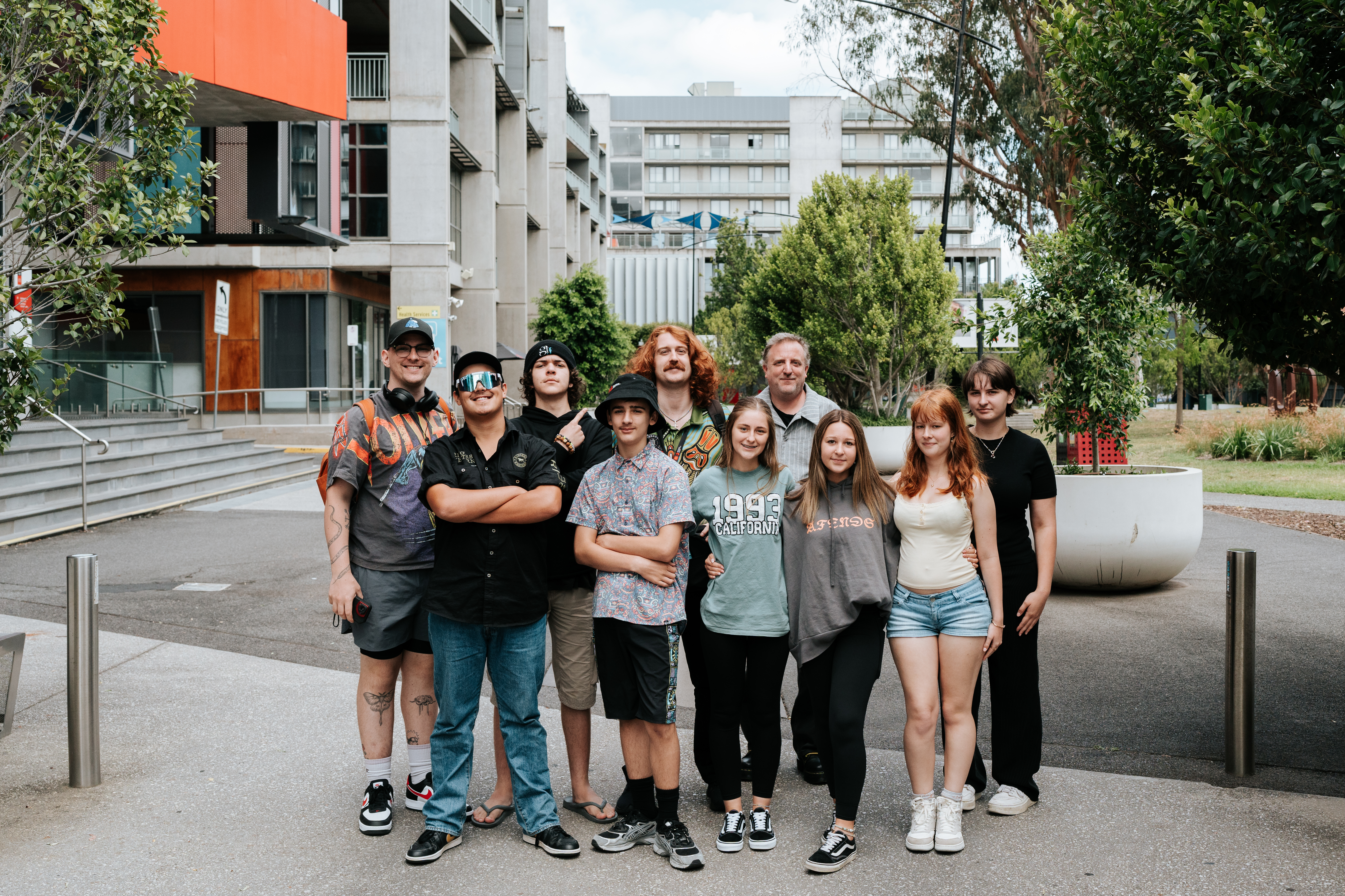 Ten young students standing together in the middle of a university street in summer.
