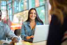 Two students get advice as they sit at a desk with a laptop