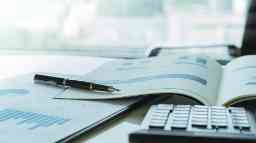 An annual business report with pages spread amongst data charts, a calculator and a pen.