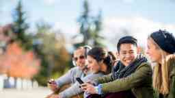 Teenage students sitting outside smiling.