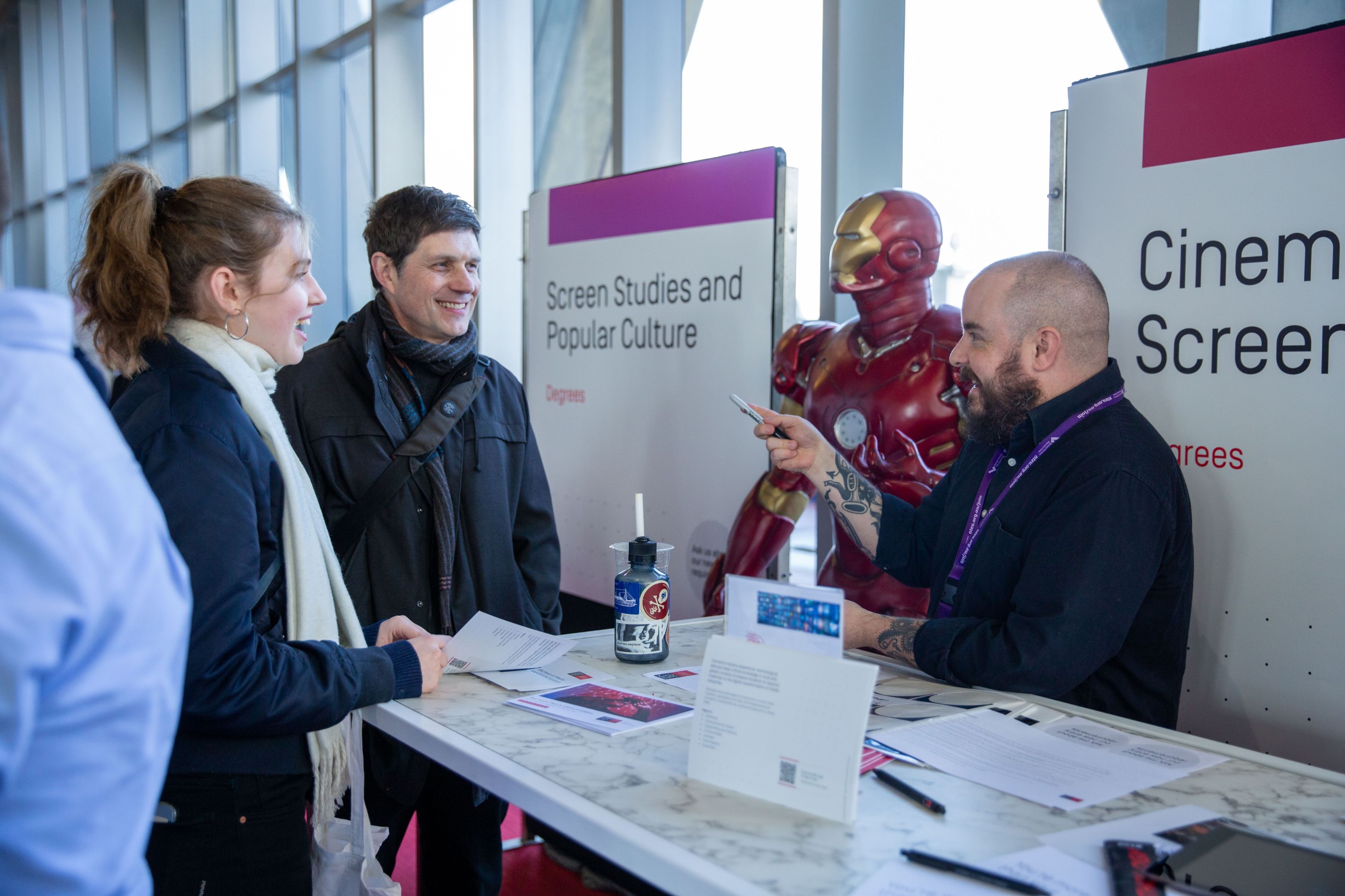 Two guests speaking with an academic at a Cinema and Screen Studies booth at Swinburne Open Day 2024. 