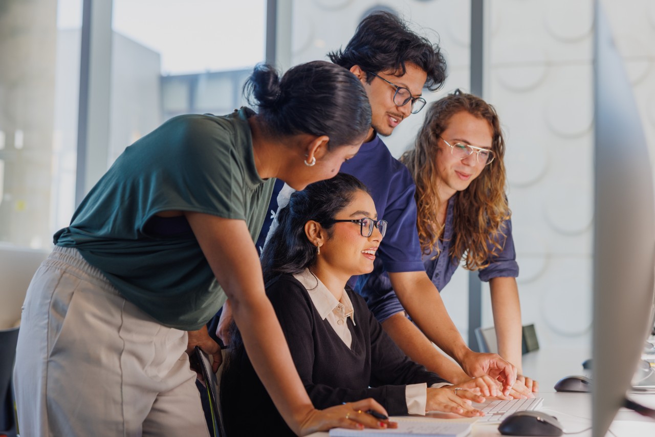 Four Swinburne students gathered around a computer in an open study space