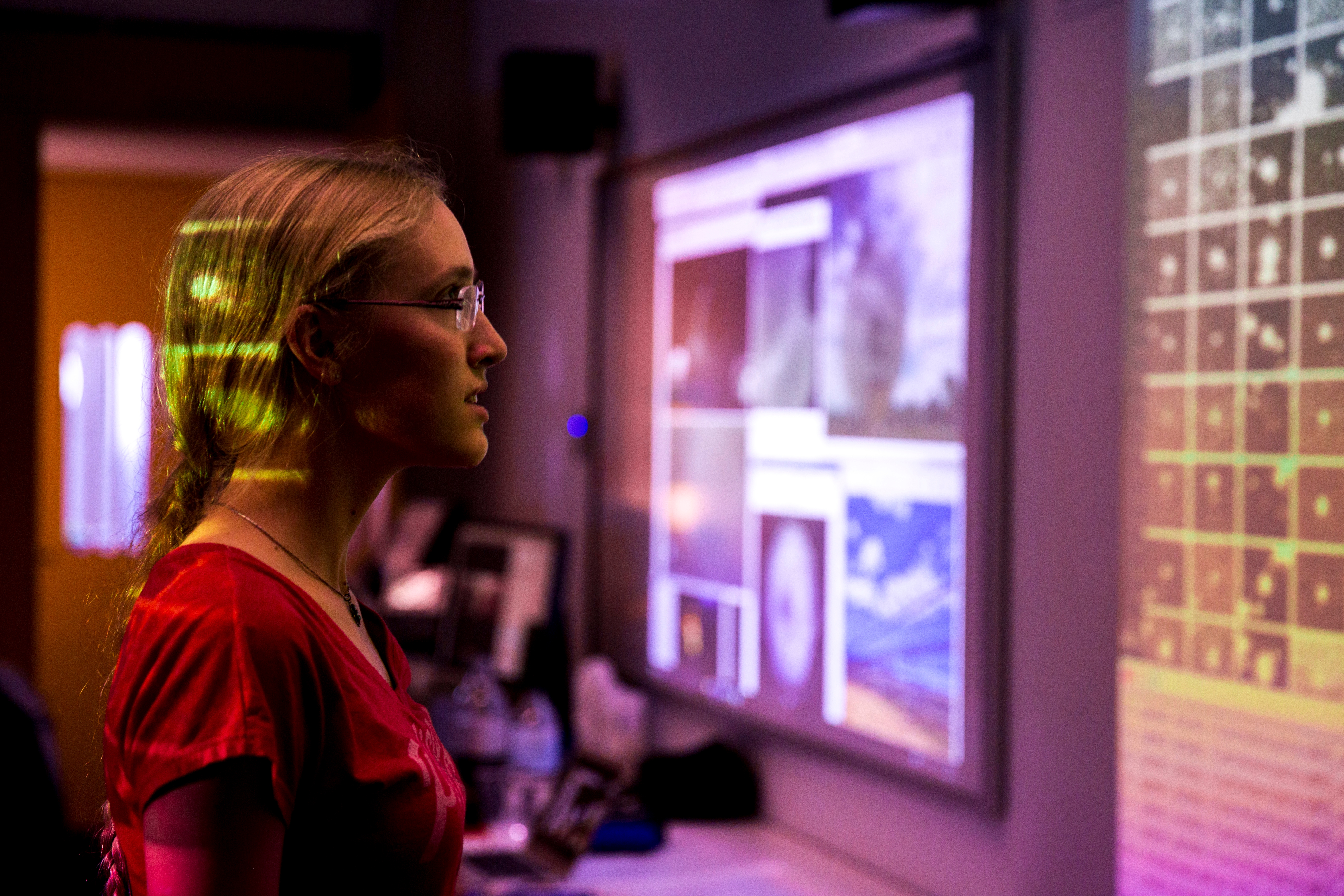 close up of woman in dim light room staring off camera at screen
