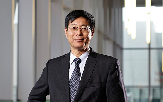 Professor Qing Long Han smiling in suit attire