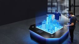 Two people with 3D glasses and wands stand around a holgram table projecting a 3D image of a city