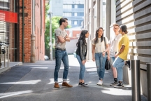 Group of 5 students chatting and walking together down McLeod Lane, between AMDC and FS buildings