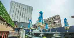Rooftop bar with picnic tables, umbrellas and large building in the background
