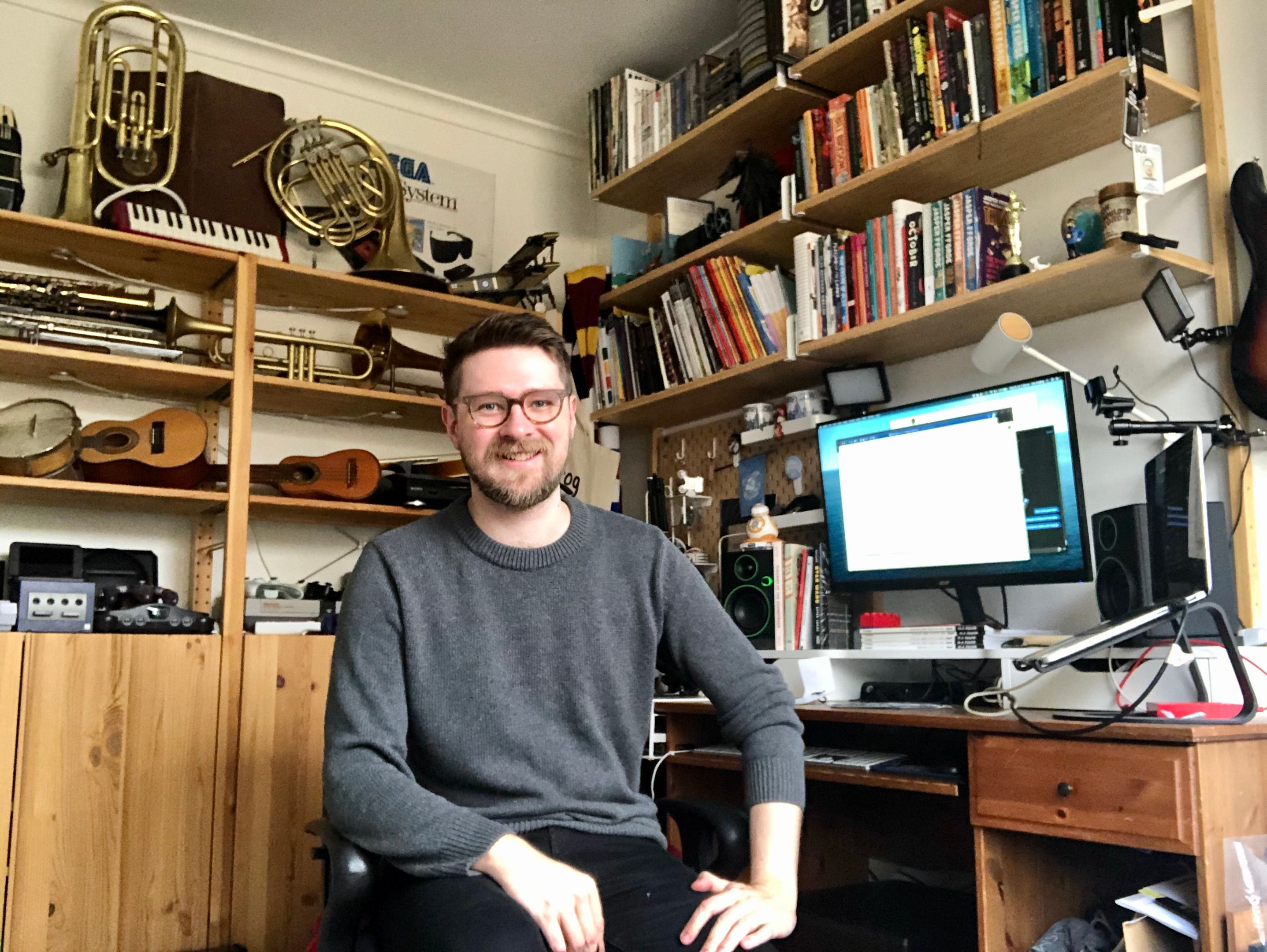 Dr Dan Golding in his home office surrounded by books and musical instruments. 