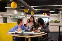 Three students around a table talking
