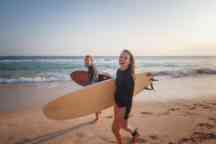 Young couple happy smiling surfers on ocean coast