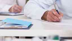 Male student writing exam paper assessment test.