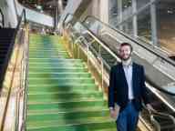 Male student walking down green stairs towards the camera