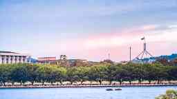 Lake Burley Griffin in Canberra against a backdrop of Australian Parliament House and the Australian flag.