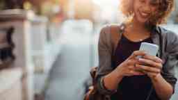 Young woman smiling whilst using her smartphone.