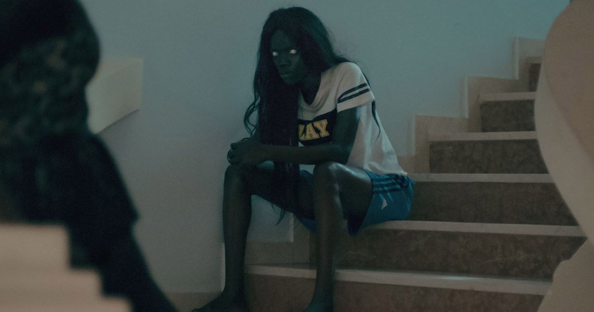 Women from Atlantics with white eyes, black hair, sitting on the bottom of  stairs. 