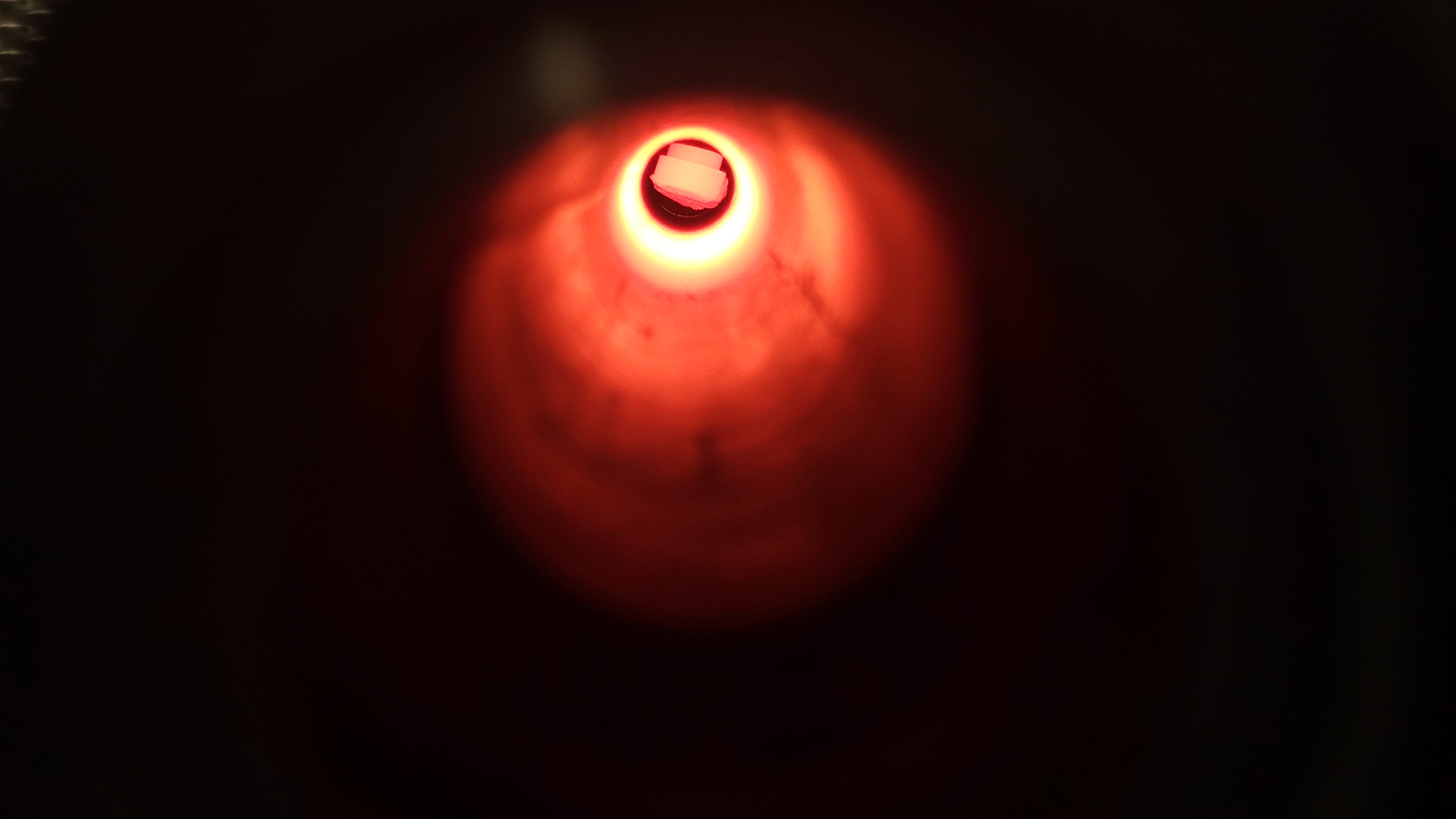 A glowing puck is seen at centre containing Martian regolith simulant. It sits inside a fainter glowing tube - the inside of a furnace that recreates Martian atmospheric pressure. When heated, metals in the regolith are extracted to form iron.