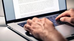 Close-up shot of a laptop and two hands typing
