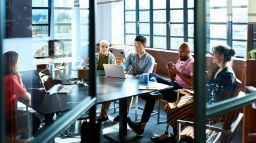 Six people having a discussion around a table in a classroom