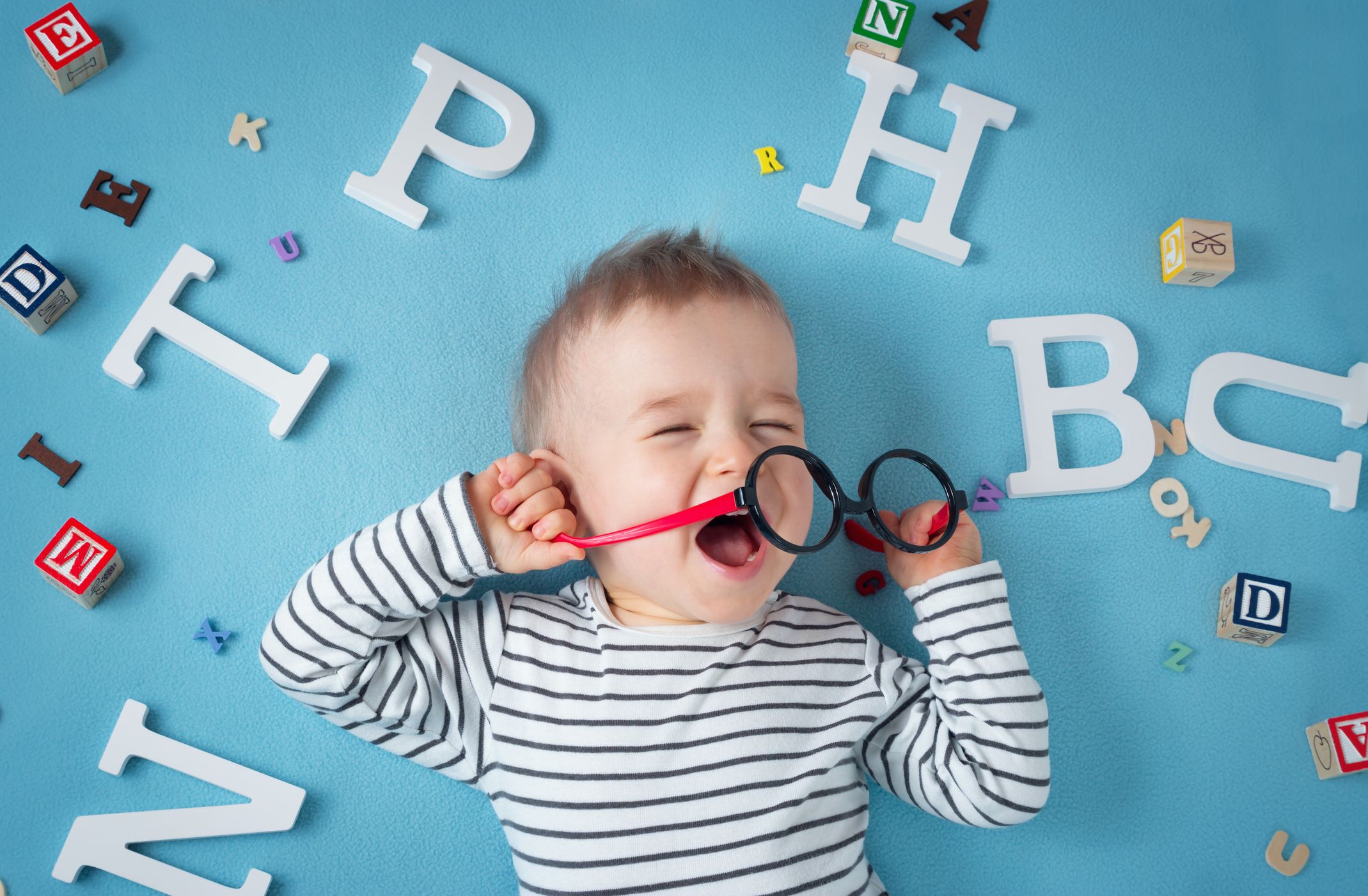 One year old child lying with spectacles and letters