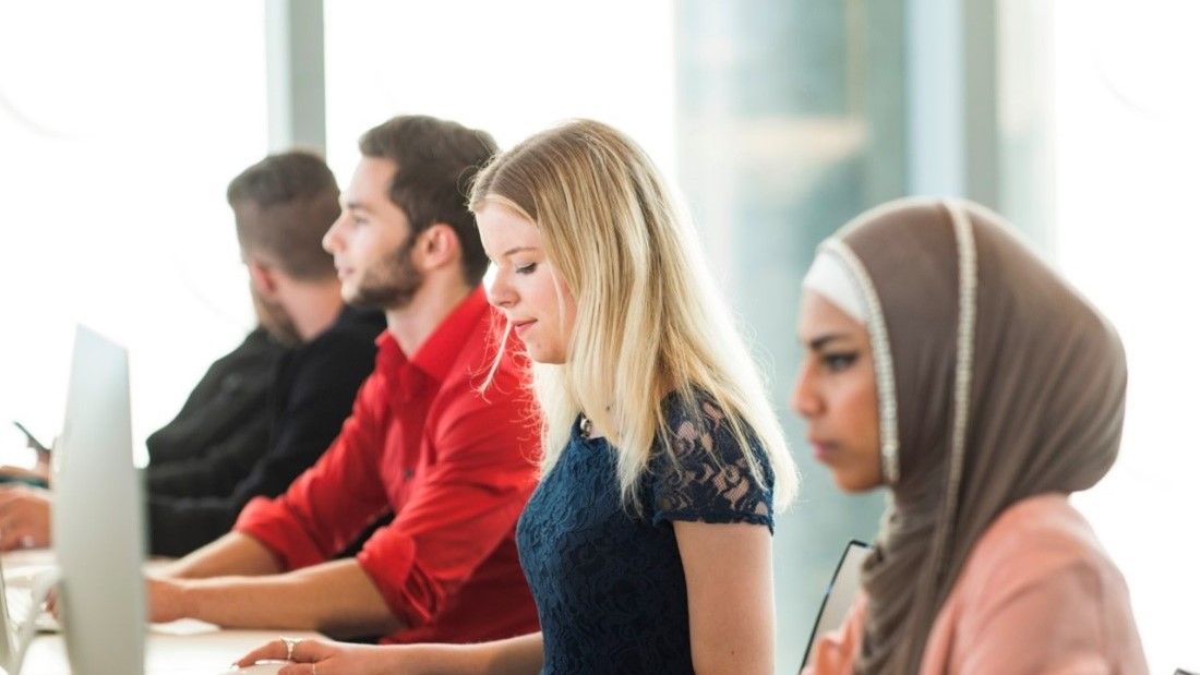 4 people working at desk.