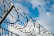 Barbed wire fence against blue sky with clouds