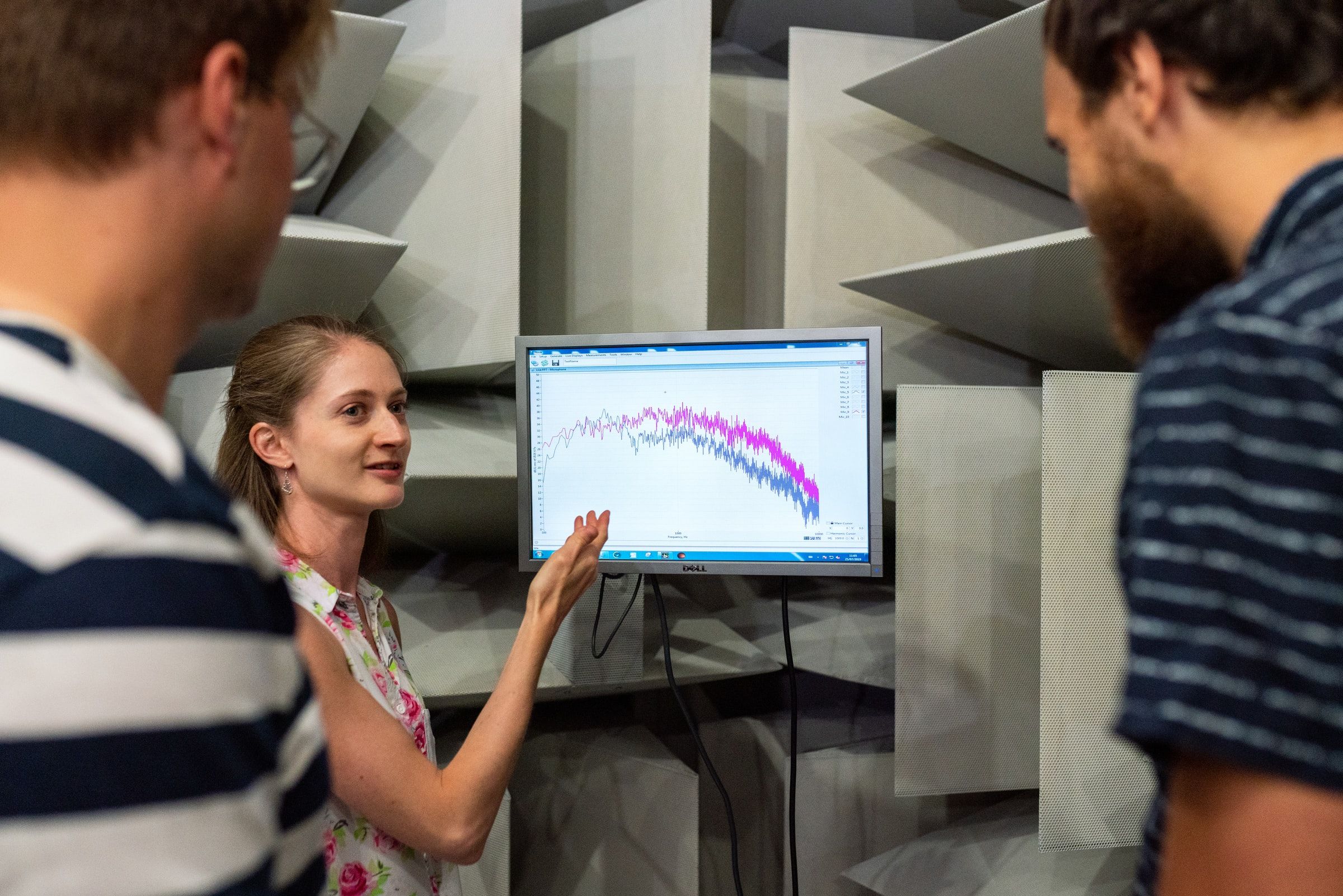 Three young people standing around a computer displaying data