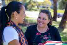 Photograph of two women smiling and talking on a campus.