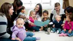 Mothers and toddlers sitting and reading in a social setting.