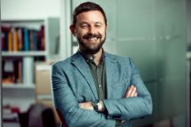 Professional looking man with a beard smiling at the camera with his arms crossed over his chest.