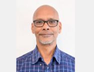 Portrait of a person wearing glasses, smiling slightly.