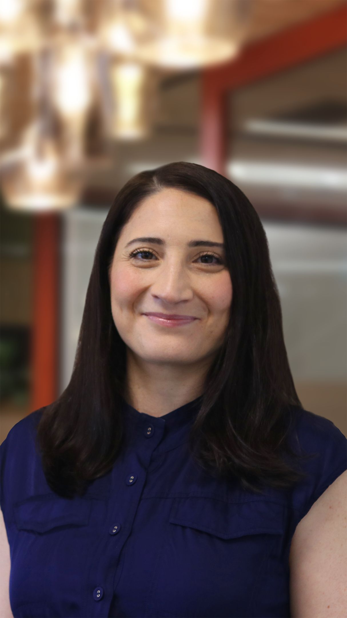 Woman with long black hair, wearing a blue blouse, smiling for the camera.