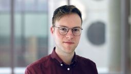 Man with short brown hair with glasses and burgandy shirt