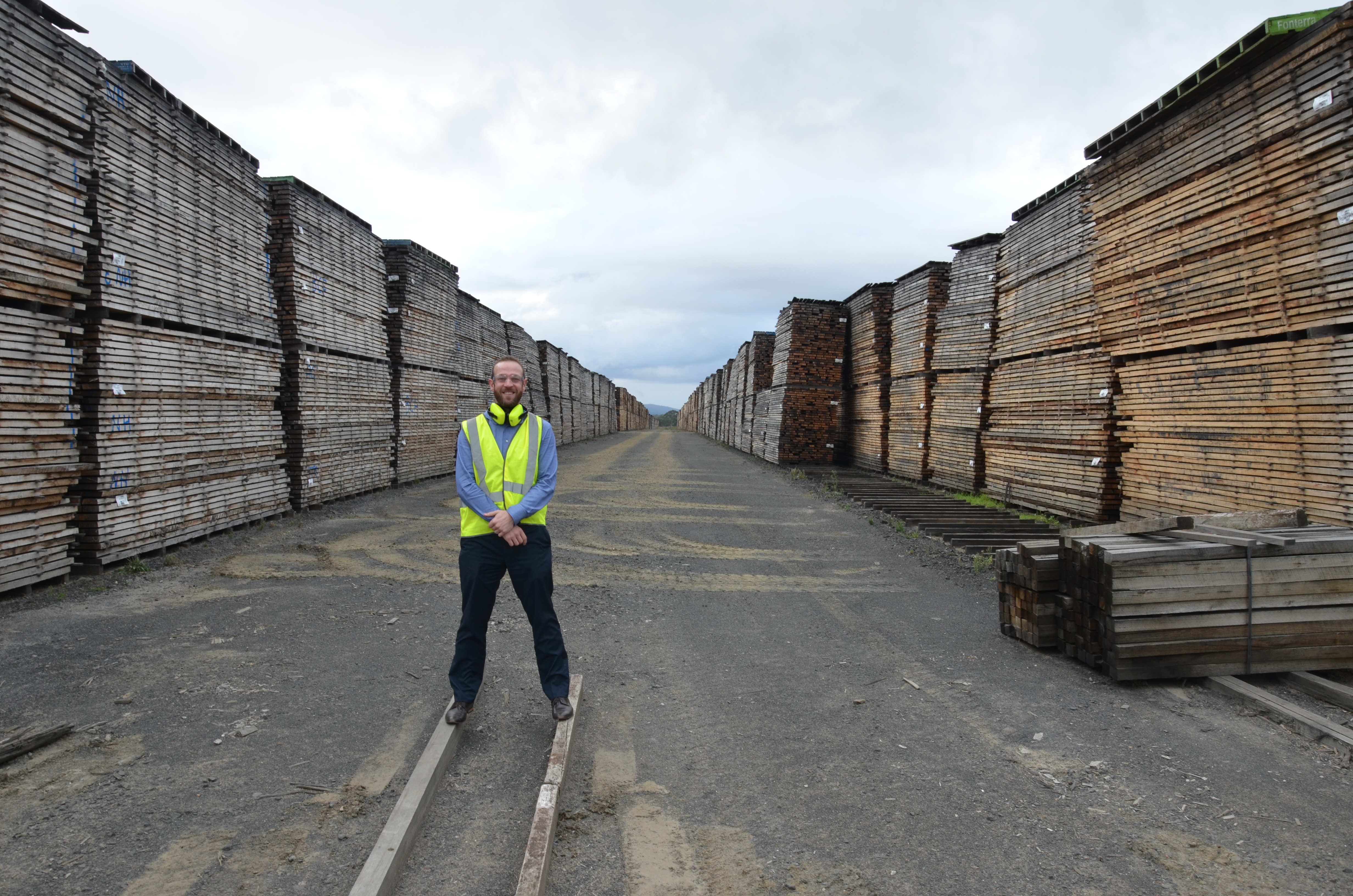 Professor Blair Kuys wearing a high visibility jacket whilst he stand in a wood yard