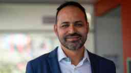 Medium close up of man standing indoors smiling at camera