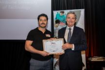 Swinburne graduate Anton Guzman stands with Chancellor of La Trobe University John Brumby AO holding up a framed certificate of Anton's award