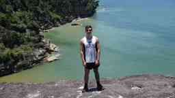 Man standing on a cliff with the coast line in the background