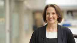 Professional female smiles to camera at the AGSE building wearing a black blazer 
