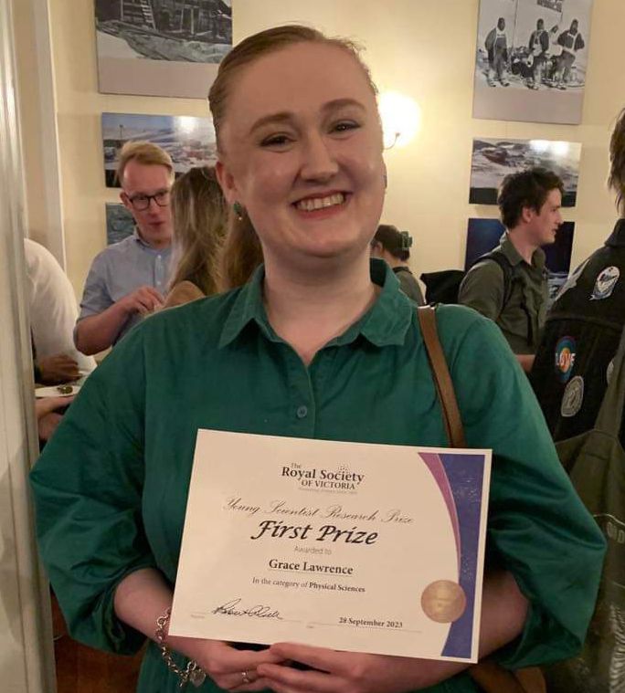 Woman smiling holding a first prize certificate from the Royal Society of Victoria