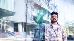 Abdullah, Master of IT (Professional Computing) student, leaning against a glass wall looking to the side and off to the distance.