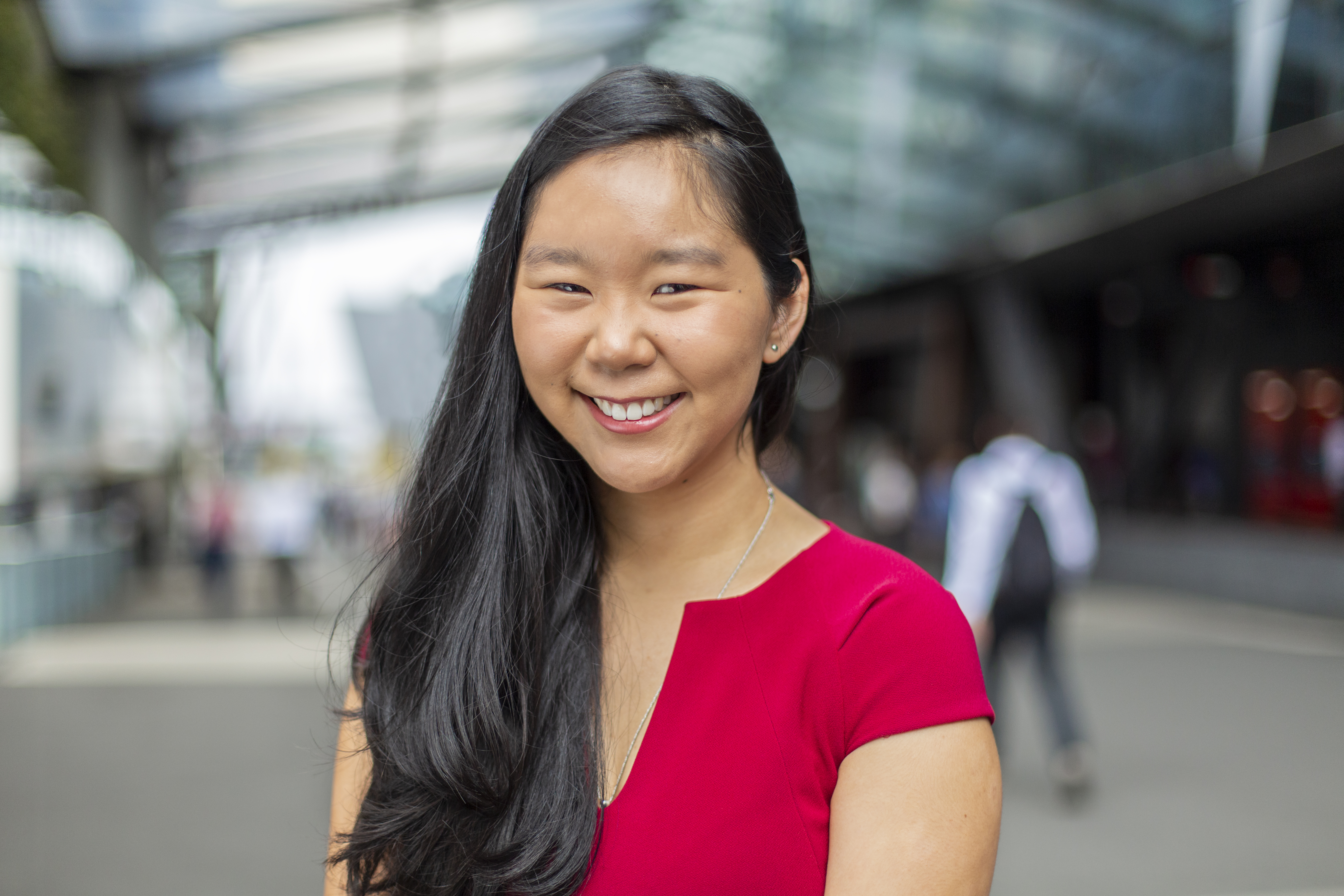 Young female international student, wearing red, smiling at the camera